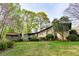 Serene backyard featuring a lush lawn, mature trees, and a charming house with a covered porch and deck at 1039 Smyrna Rd Sw, Conyers, GA 30094