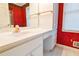 Bathroom with white vanity, marble counter, and bright red wallpaper at 1039 Smyrna Rd Sw, Conyers, GA 30094