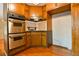 Corner view of a kitchen featuring stainless steel oven, wood cabinets, and brick fireplace in an adjoining room at 1039 Smyrna Rd Sw, Conyers, GA 30094