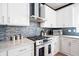 Kitchen boasts white cabinetry, stone backsplash, granite countertops, and stainless steel oven and range hood at 13070 Tidewater Xing, Alpharetta, GA 30005