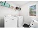 Bright laundry room featuring washer, dryer, overhead storage, and a window at 13070 Tidewater Xing, Alpharetta, GA 30005