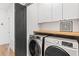 Modern laundry room featuring front-load washer and dryer, storage cabinets, and hardwood flooring at 2424 Memorial Se Dr # 3, Atlanta, GA 30317