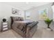 Cozy bedroom featuring a plush bed with a gray tufted headboard and a bright window view at 2770 Westgate Park Dr, Loganville, GA 30052