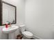 Elegant powder room with pedestal sink, white toilet, decorative mirror and stylish flooring at 2770 Westgate Park Dr, Loganville, GA 30052