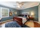 Comfortable bedroom with a large window, ceiling fan, dark wood furniture, and wood floors at 640 Saddle Ridge Trce, Roswell, GA 30076