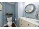 Charming powder room featuring blue walls, a stylish round mirror, and a classic vanity at 640 Saddle Ridge Trce, Roswell, GA 30076