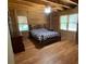 Rustic bedroom featuring hardwood floors, wood-paneled walls and a ceiling fan for added comfort at 5098 Meadows Rd, Powder Springs, GA 30127