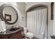Bathroom featuring dark wood vanity, large oval mirror, toilet and shower with geometric curtain at 1754 Water Springs Way, Dacula, GA 30019