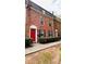 Charming two-story brick townhouse featuring a red door and lush green landscaping at 115 Winding River Dr # B, Atlanta, GA 30350