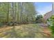 A spacious backyard with lawn, trees, wooden fence, and patio with fire pit at 302 Wickley Way, Woodstock, GA 30188