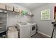 Functional laundry room with washer, dryer, shelving, and ample storage space at 3978 Oak Crossing Drive Dr, Suwanee, GA 30024