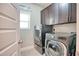 Modern laundry room featuring front load washer and dryer and dark brown cabinets at 453 Thorn Creek Way, Dallas, GA 30157