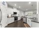 Well-lit kitchen boasts stainless appliances, sleek white cabinets, and a view into the adjacent dining area at 216 Ellis Ln, Woodstock, GA 30189