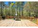 Spacious wooden deck, perfect for outdoor relaxation, surrounded by a lush, green forest and a table and chairs at 285 Willow Shoals Dr, Covington, GA 30016
