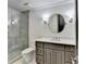 Modern bathroom featuring a glass-enclosed shower, grey vanity, and round mirror with decorative lighting at 4505 Whitestone Way, Suwanee, GA 30024