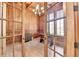 Wood-paneled home office with large windows and elegant chandelier viewed through glass doors at 4505 Whitestone Way, Suwanee, GA 30024