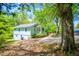 Side angle of a two-story light blue cottage with a welcoming porch, green surroundings, and a spacious driveway at 8211 Thompson St, Douglasville, GA 30134