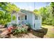 Side view of a cozy blue house featuring a covered porch, white trim, and vibrant pink flowers in the yard at 8211 Thompson St, Douglasville, GA 30134
