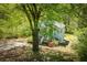 View of cozy cottage-style home nestled among mature trees and plants, featuring a quaint front porch at 8211 Thompson St, Douglasville, GA 30134