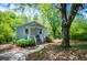 Charming blue cottage with white trim, inviting front porch, and lush landscaping with a large tree at 8211 Thompson St, Douglasville, GA 30134