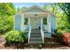 Quaint light blue home with white trim, a covered entry, and blossoming pink azaleas accenting the front yard at 8211 Thompson St, Douglasville, GA 30134
