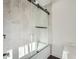 Modern bathroom featuring a tub with a glass shower door and marble-style tile at 3214 Cedar Bluff Ne Dr, Marietta, GA 30062
