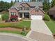 Aerial view of brick home showing manicured lawn, two-car garage, and inviting front porch perfect for relaxing and enjoying the neighborhood at 4650 Brighton View Trl, Cumming, GA 30040
