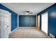 Stylish bedroom featuring a blue accent wall, plush carpet, and a ceiling fan at 4992 Meadow Ln, Marietta, GA 30068