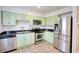 Well-lit kitchen with stainless steel appliances, light green cabinets, and dark countertops at 4992 Meadow Ln, Marietta, GA 30068