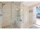 Bright bathroom featuring a glass-enclosed shower with decorative tile accents, a built-in bench, and stone tile flooring at 3235 Roswell Ne Rd # 721, Atlanta, GA 30305