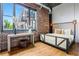 Bright bedroom with exposed brick, hardwood floors, and large windows showcasing city views at 3235 Roswell Ne Rd # 721, Atlanta, GA 30305