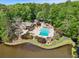 Aerial view highlights a pool and lake, nestled amongst lush trees, offering serene waterfront living at 4553 Pond Ln, Marietta, GA 30062