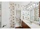 Bathroom with floral wallpaper, white vanity, and a view of the adjacent toilet and sink area at 4553 Pond Ln, Marietta, GA 30062