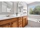 Bathroom featuring double sinks, wood cabinets, and a soaking tub near a bright window at 5317 Concordia Se Pl # 10, Mableton, GA 30126