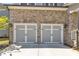 Close-up of a two-car garage featuring gray doors, stone facade, and decorative black hardware at 5382 Pebblebrook Se Ln, Mableton, GA 30126