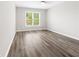 Bedroom featuring wood-look floors, neutral paint, and natural light from a large window at 3 S Riversong Ln, Alpharetta, GA 30022