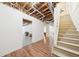 Unfinished basement with exposed ceiling and ductwork, wood laminated flooring and stairs at 45 Harvey Ave, Covington, GA 30016