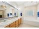 Bright bathroom featuring a double vanity, large mirror and separate soaking tub with tile surround at 45 Harvey Ave, Covington, GA 30016
