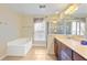 Bright bathroom featuring a soaking tub, glass-enclosed shower, and double vanity with a neutral countertop at 4880 Payson Se Ter, Atlanta, GA 30339