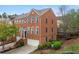 Attractive three-story brick townhome with attached garage, landscaped front yard, and welcoming entryway stairs at 4880 Payson Se Ter, Atlanta, GA 30339