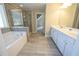 Luxurious bathroom showcasing a soaking tub, glass-enclosed shower, double vanity, and tile flooring with easy access to additional rooms at 2034 W Hampton Dr, Canton, GA 30115