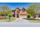 Two story brick home features manicured lawn, two car garage, and mature landscaping at 2424 Malden Park Dr, Buford, GA 30519