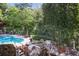 Community pool area featuring a waterfall, mature trees, and comfortable lounge chairs at 200 River Vista Dr # 423, Atlanta, GA 30339