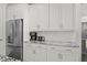 This kitchen features stainless steel refrigerator and coffee maker and granite countertops and white cabinets at 74 Academy St, Alpharetta, GA 30009
