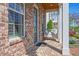 Inviting brick porch featuring a cozy porch swing, white columns, and a glimpse of the well-manicured landscaping at 74 Academy St, Alpharetta, GA 30009
