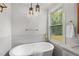 Bright bathroom featuring freestanding tub with gold fixtures, window and pendant lights at 2374 Marion Cir, Decatur, GA 30032