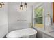 Modern bathroom with a freestanding tub, pendant lights, and a view to the backyard at 2374 Marion Cir, Decatur, GA 30032