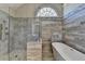 Modern bathroom showcasing a glass shower and standalone tub, lit by a arched window at 3237 Birkdale Ave, Duluth, GA 30097