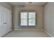 An empty carpeted bedroom with a window and closet doors, showcasing neutral decor at 3237 Birkdale Ave, Duluth, GA 30097
