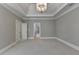 A spacious bedroom featuring tray ceilings, an elegant chandelier, and view leading to other rooms at 3237 Birkdale Ave, Duluth, GA 30097